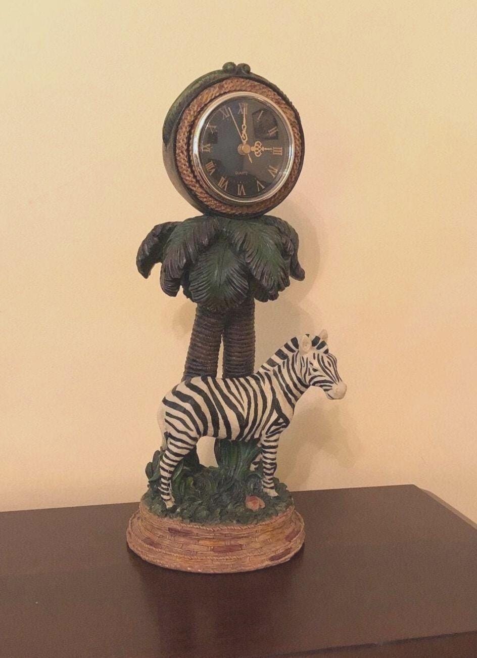Zebra Clock Sculptured in the Grass with Palm Trees.  5" x 6" x 15" high. Clock works with AA battery, not included.  Excellent Condition